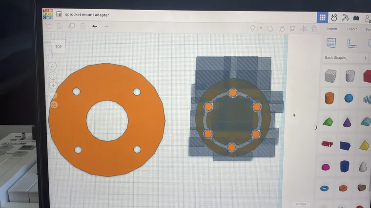 A CAD screen showing an orange circular motor flange being modelled.