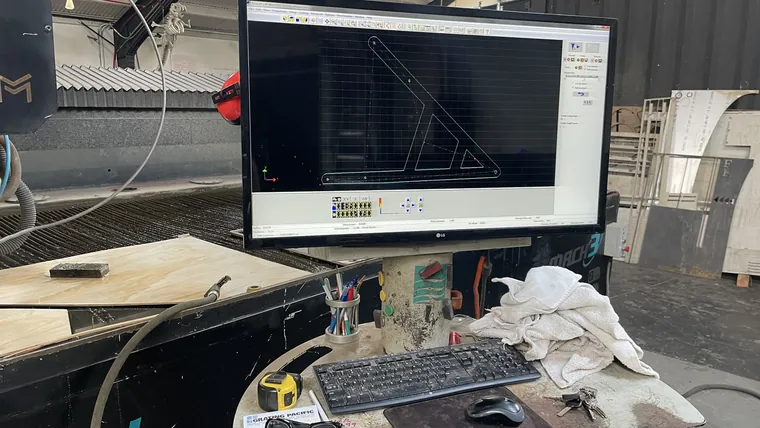 A workshop monitor showing a CAM toolpath for one of the frame plates.