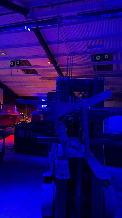 The forklift under blue workshop lighting, used as a lifting rig.