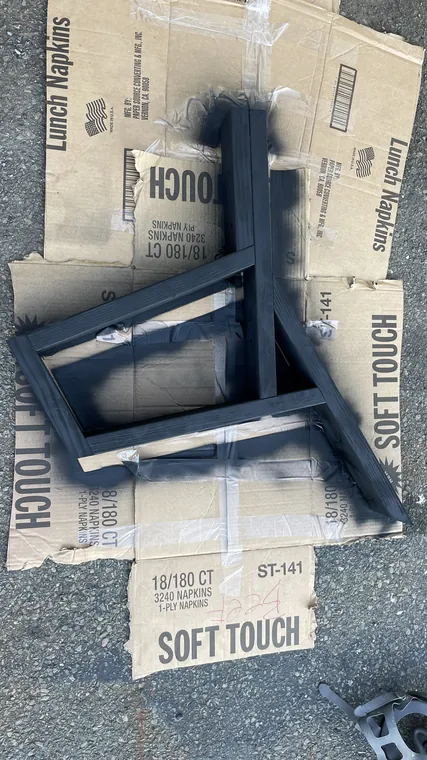 The wooden frame painted black, resting on flattened cardboard outside.