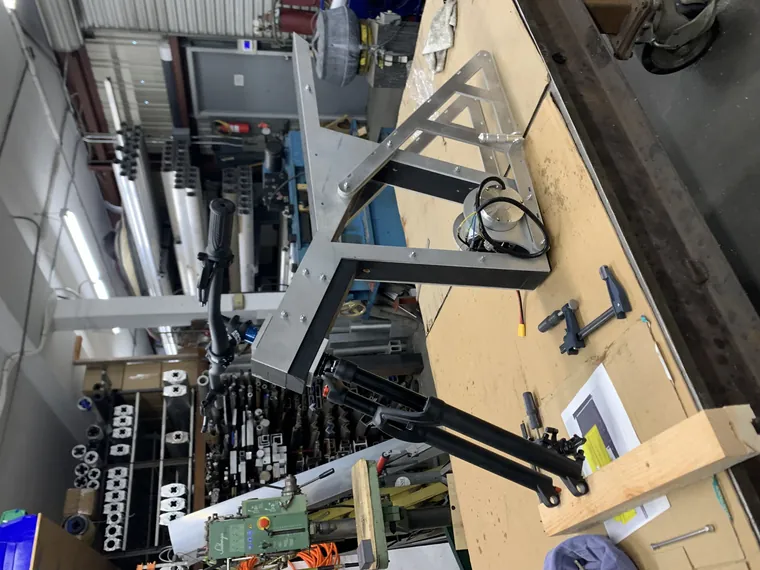 Frame parts and suspension forks hanging in the workshop.