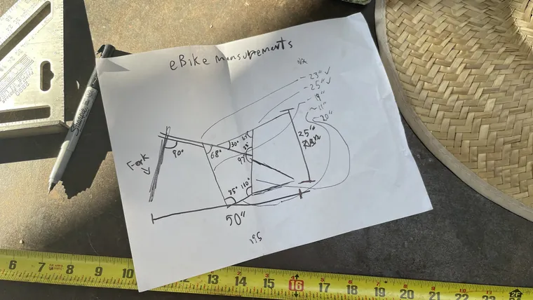 A hand-drawn frame sketch with angles and dimensions, next to a tape measure.
