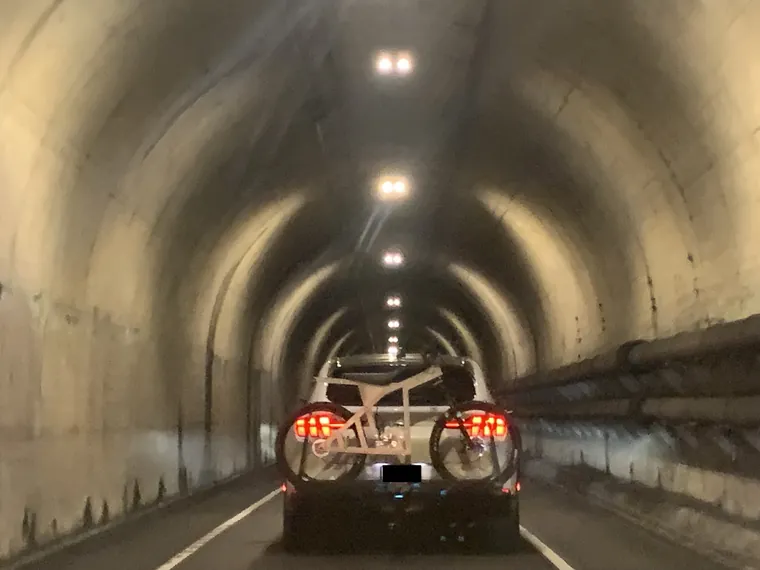 Two bikes on a car rack, seen through a road tunnel.