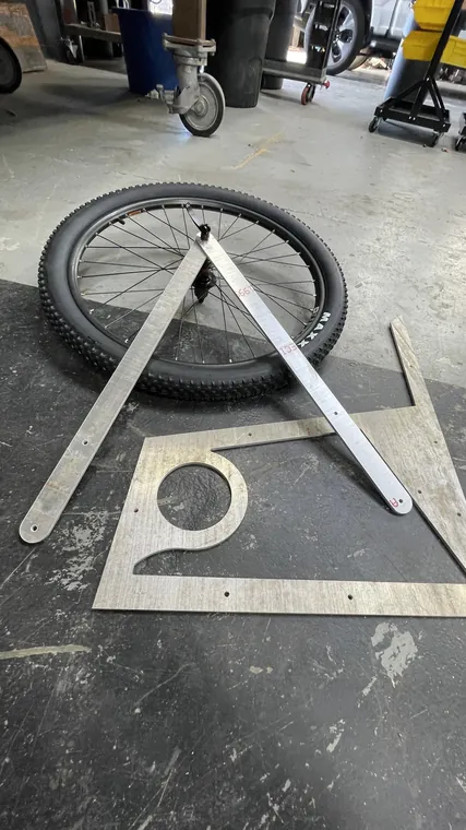 Two wheels laid out beside cut aluminum plate frame sections.
