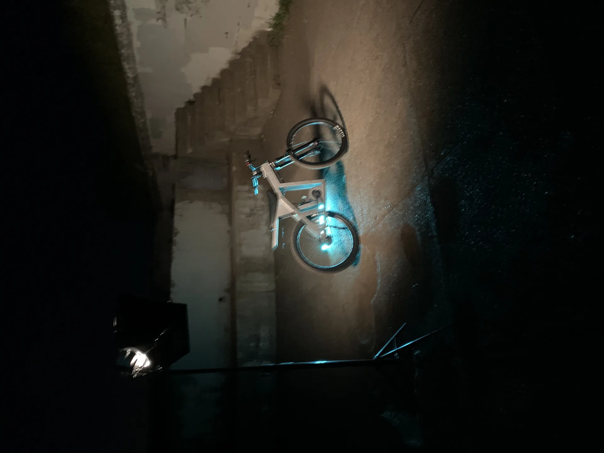 The Nacho parked in a dark garage, its frame outlined by teal light.